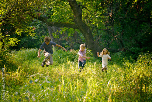 Three blond children running  in a beautiful countrymeadow. photo