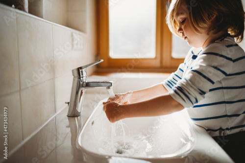 Side view of young preschool aged child washing hands with soap photo