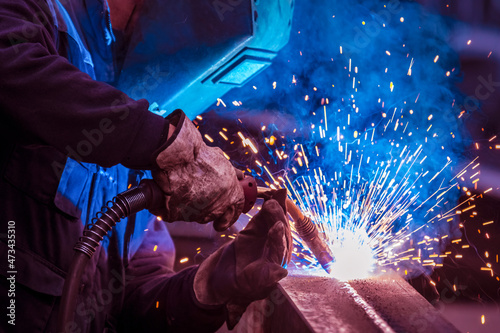 Man with face and eye protection shield welding steel girder
