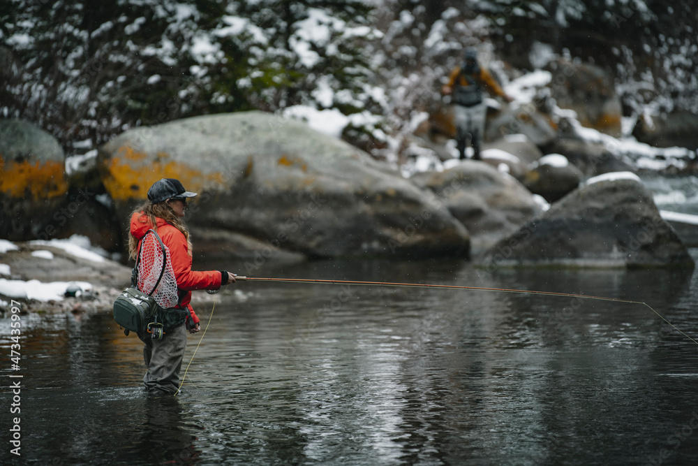 Side view of woman fly fishing while standing in river during winter Side view of woman fly fishing while standing in river during winter