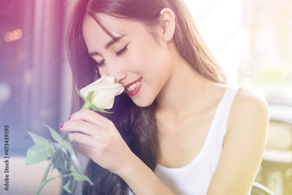 Young beautiful Asian woman holding a white rose in Valentine’s Day and enjoying its smell Young beautiful Asian woman holding a white rose in Valentine’s Day and enjoying its smell
