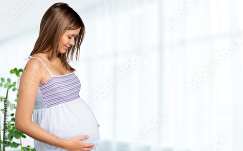 Side view of a beautiful pregnant woman standing near window at home Free Download Side view of a beautiful pregnant woman standing near window at home - GFXLoad