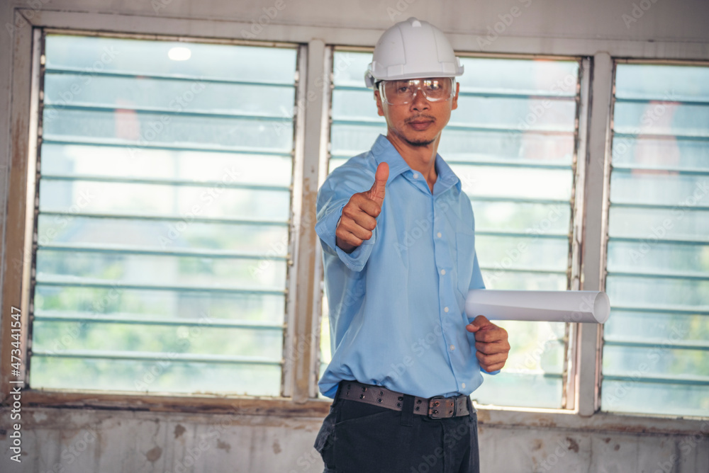 Construction engineer man hold blueprint wear blue shirt safety white hard hat at construction site industry labor worker. Architecture man engineer civil worker look at blueprint real estate concept Construction engineer man hold blueprint wear blue shirt safety white hard hat at construction site industry labor worker. Architecture man engineer civil worker look at blueprint real estate concept