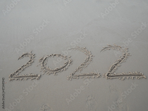 written word 2022 on the sand beach New year concept.