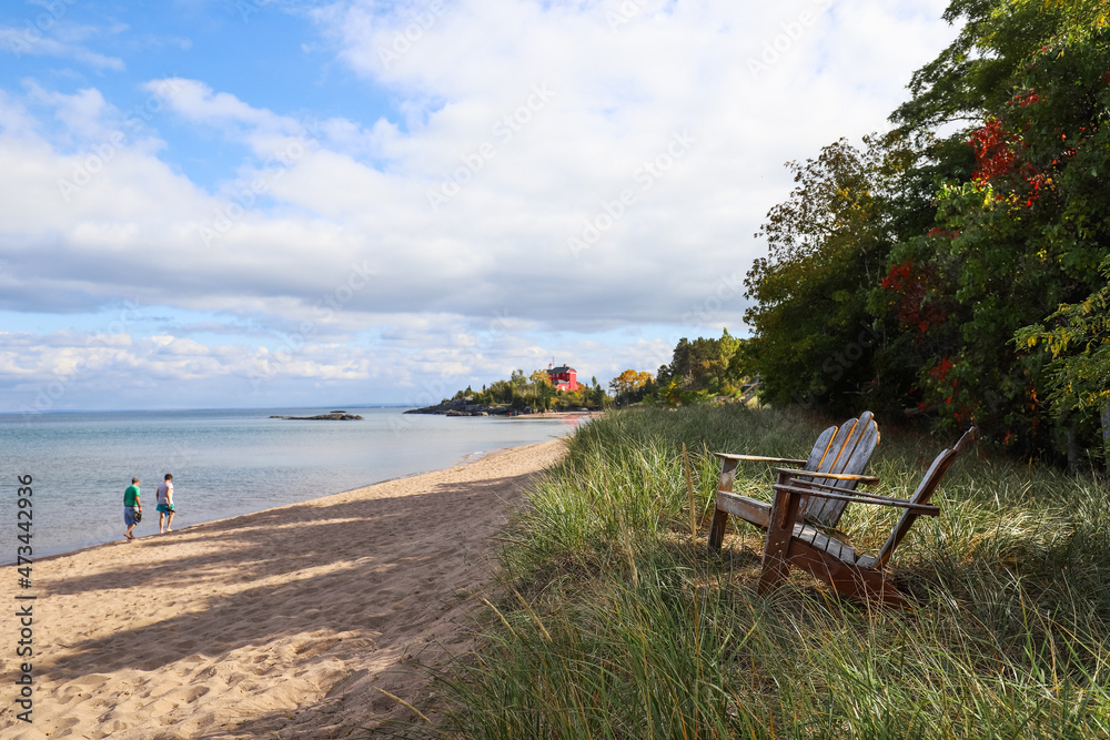 Adirondack chairs on the shore of Lake Superior in Marquette, Michigan. Harbor Lighthouse in the background, focus on chair in foreground