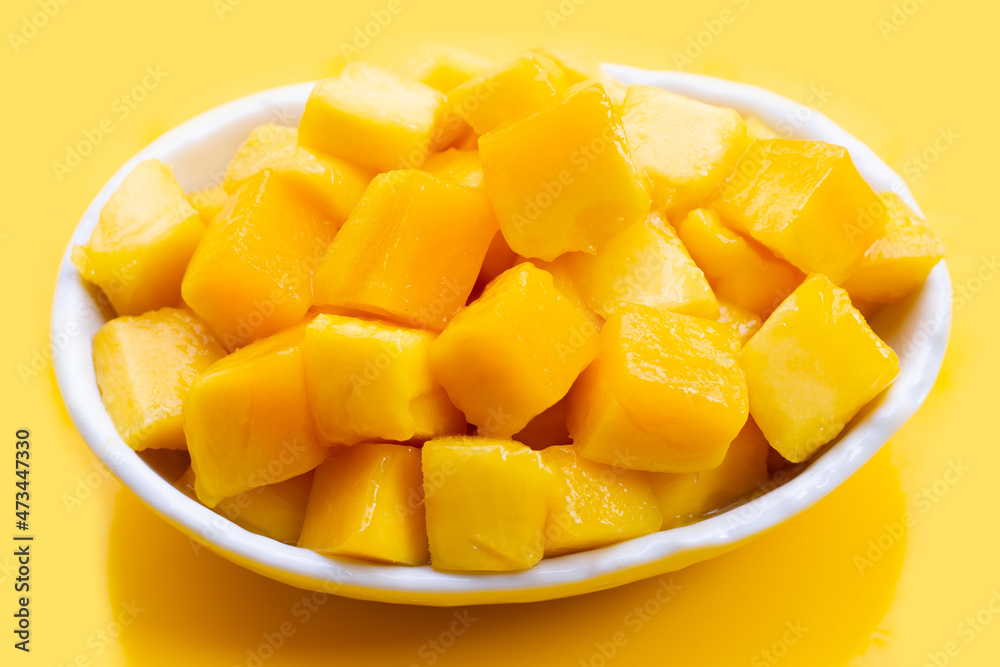 Tropical fruit, Mango cube slices in white bowl on yellow background.