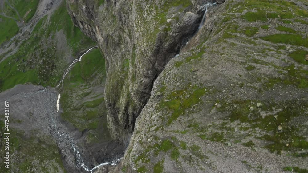 Aerial drone rotating bird's eye view of a waterfall falling from the high mountainous terrain on to the plains. Narrow streams joining to become a river. Aerial drone rotating bird's eye view of a waterfall falling from the high mountainous terrain on to the plains. Narrow streams joining to become a river.