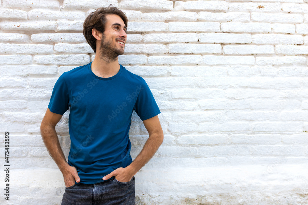 Smiling confident young caucasian man standing next to white brick wall. Copy space. Smiling confident young caucasian man standing next to white brick wall. Copy space.