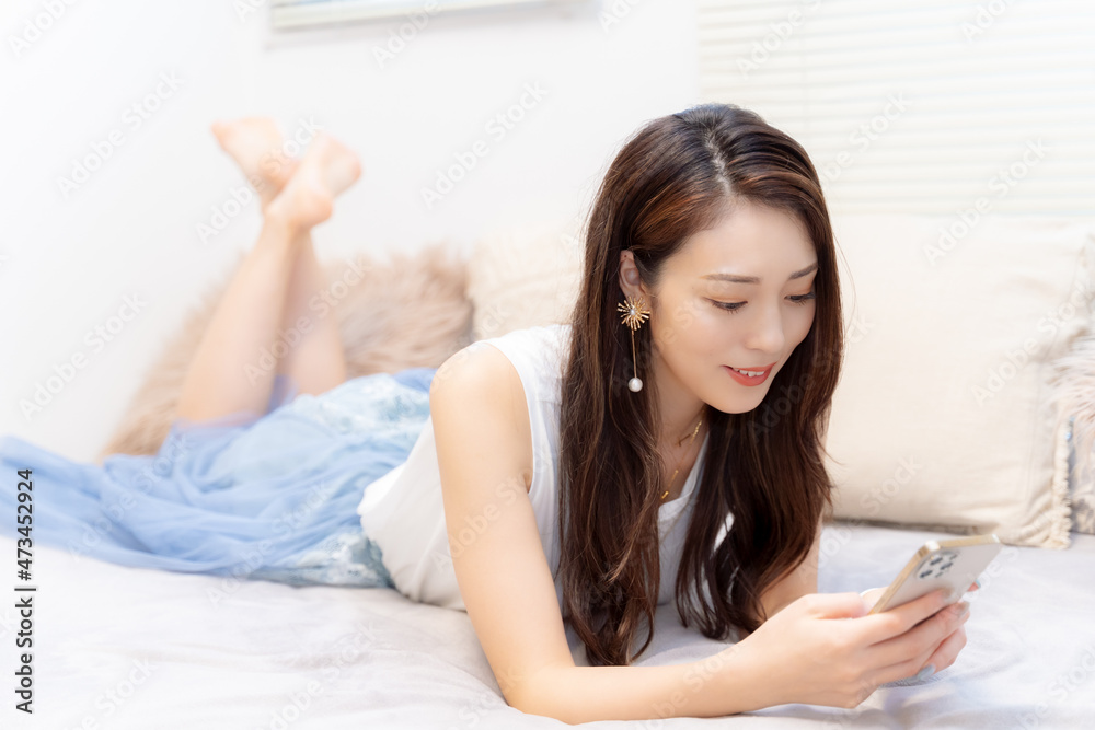 ベッドでゴロゴロしながらスマホを見る女性 Stock Foto Adobe Stock ベッドでゴロゴロしながらスマホを見る女性 Stock Foto Adobe Stock