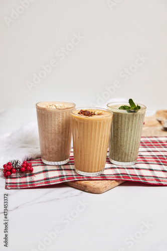 Fototapeta Naklejka Na Ścianę i Meble -  Three holiday smoothies on a white background with festive decor