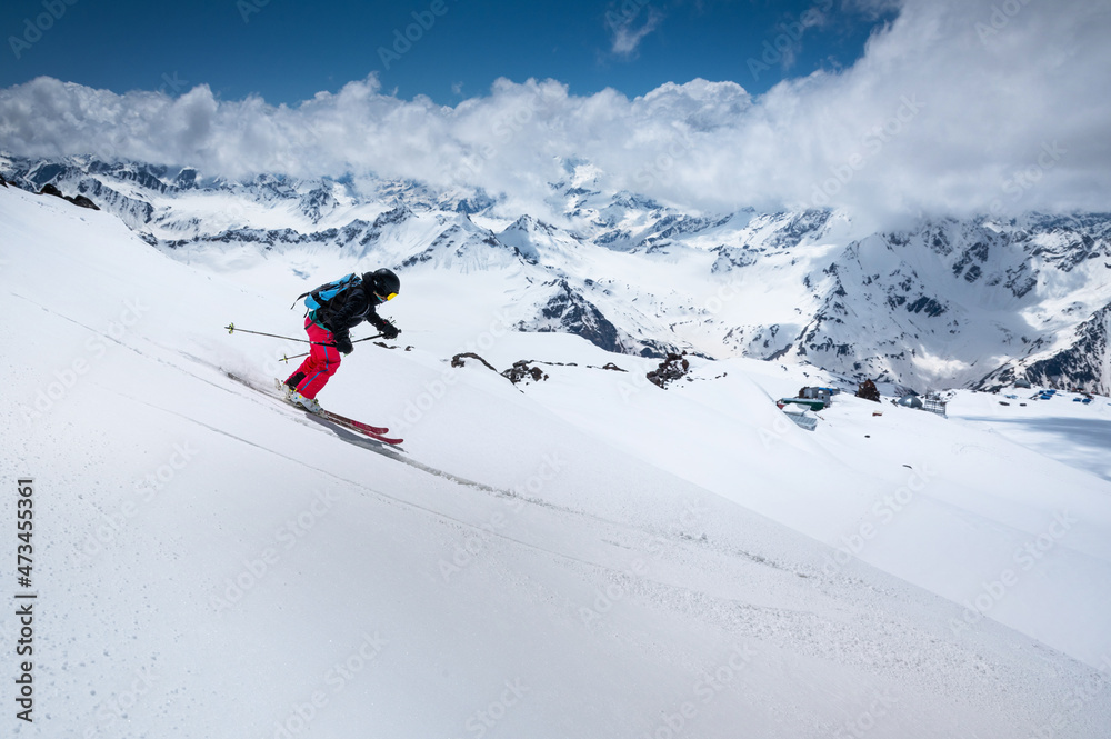 Woman Skier skiing downhill in high mountains against mountains and clouds.