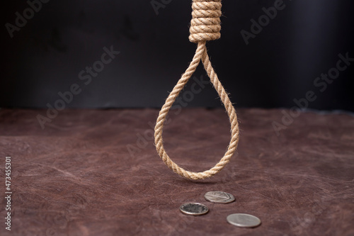 Fotografía hangman's noose hanging over 3 silver coins on brown leather background