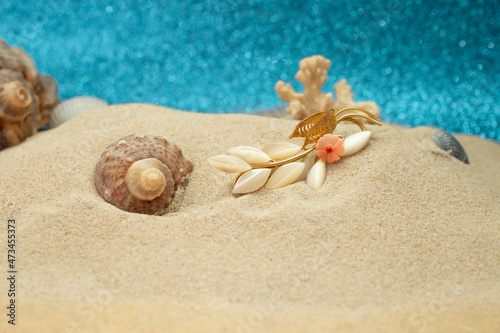 sea side inspired jewelry in the sand, with seashells and coral