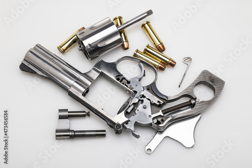 Dismantling a revolver hand gun with bullets on a white background
