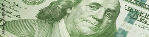 American paper money. A $100 bill with focus on eyes of Benjamin Franklin. US banknotes close-up. Business economy and the USA dollar. Light green tinted banner or headline. Macro