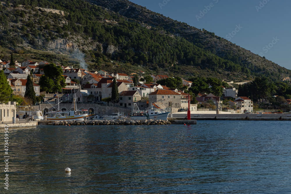 Beautiful beach marina waterfront of Bol on Brac, old city with picturesque mountanious backdrop. View from harbor.