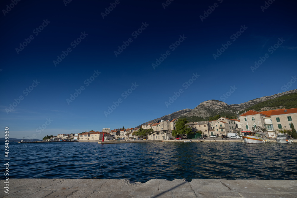 Beautiful beach marina waterfront of Bol on Brac, old city with picturesque mountanious backdrop. View from harbor.