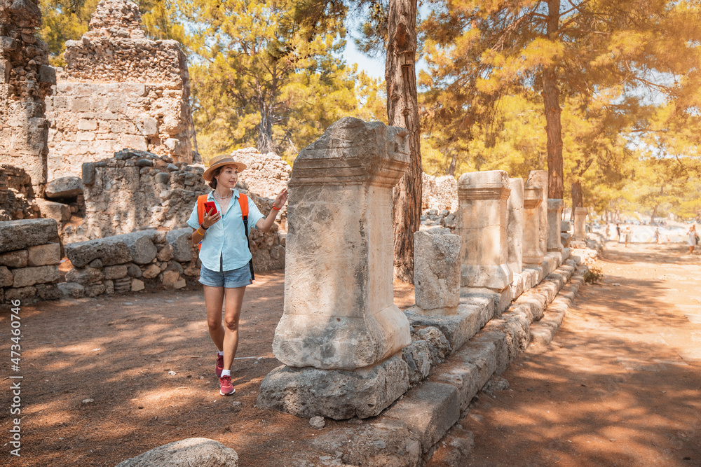 Female traveler walks through the ancient ruins of the antic Greek city of Phaselis in Turkey. Historical sights and archeology