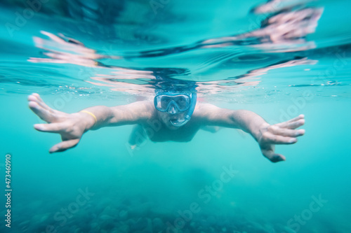 A young and happy man enjoys snorkeling underwater at an amateur level. Photo underwater with a narrow depth of field