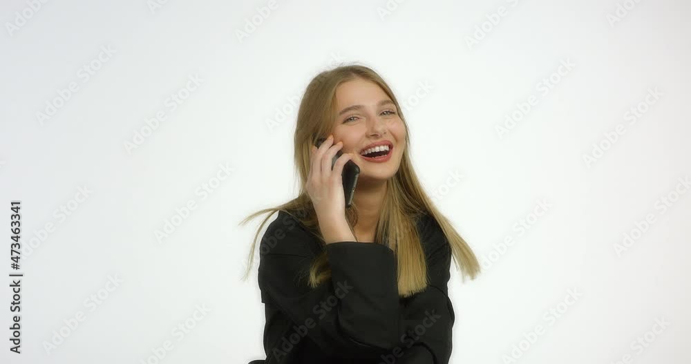 Happy woman with long blond hair is talking on the phone and laughing. Girl model straightens her hair and smiles in the studio at the camera in the studio on a white background. Happy woman with long blond hair is talking on the phone and laughing. Girl model straightens her hair and smiles in the studio at the camera in the studio on a white background.
