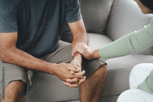 Female friend or family sitting and hold hands during cheer up to mental depress man, Psychologist provides mental aid to patient. PTSD Mental health concept.