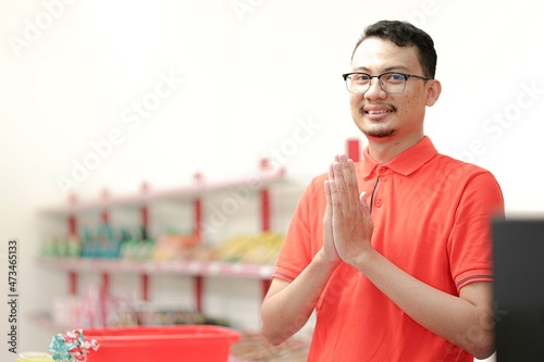 Smiling young man cashier with a welcome greeting hand gesture