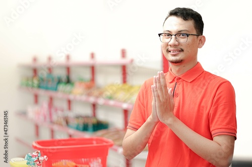 Smiling young man cashier with a welcome greeting hand gesture