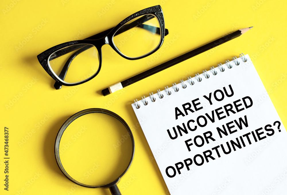 Are you uncovered for new opportunities is Motivational text on notepad with glasses, pencil and magnifier