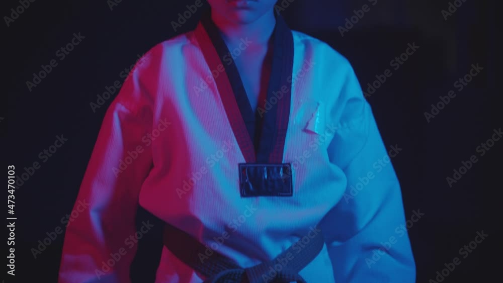 A little boy doing martial arts in the dark with neon lighting - standing in the position
