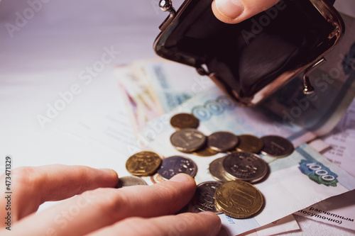 Selective focus. Russian coins and banknotes. The hand is holding an empty wallet, the second hand is counting the coins - close-up. photo