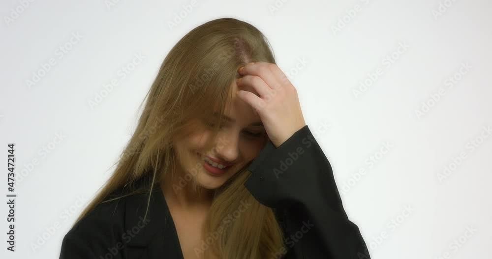 Beautiful young woman straightens her hair and poses in the studio in front of the camera on a white background. Model girl with long blonde hair in a black shirt smiles.A beautiful female face. Beautiful young woman straightens her hair and poses in the studio in front of the camera on a white background. Model girl with long blonde hair in a black shirt smiles.A beautiful female face.