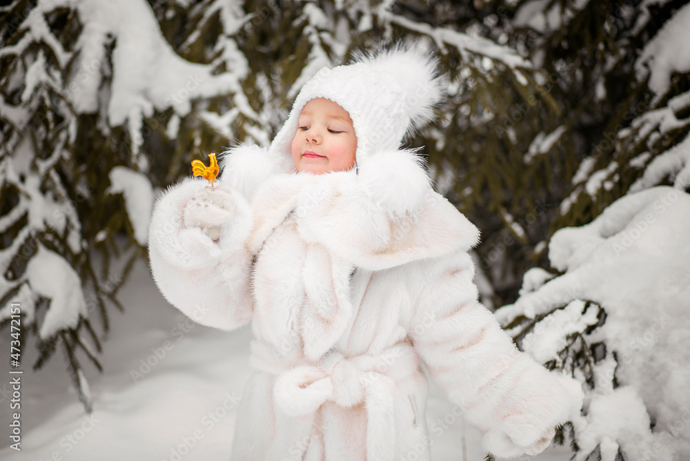 Girl in white hat and fur coat with lollipop in winter snowy forest Girl in white hat and fur coat with lollipop in winter snowy forest