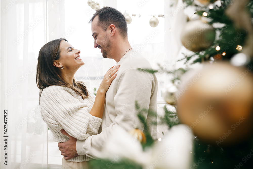 Young couple hugging near Christmas tree at home Young couple hugging near Christmas tree at home