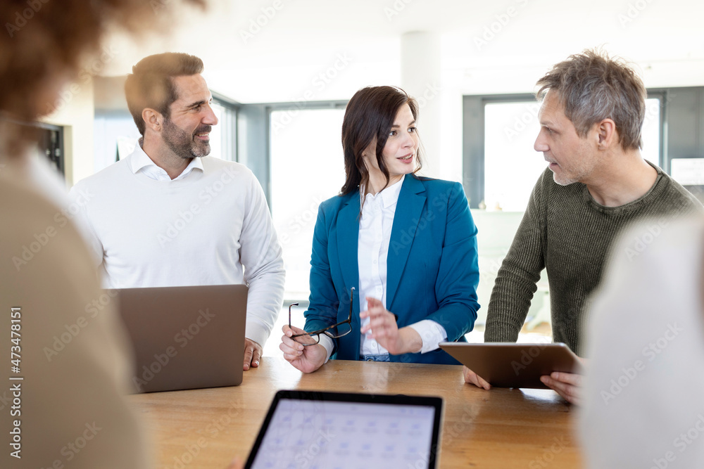 Businesswoman looking at male professional discussing strategy during meeting in office Businesswoman looking at male professional discussing strategy during meeting in office
