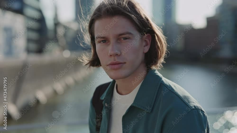 Handsome guy with trendy haircut looking at camera outdoors