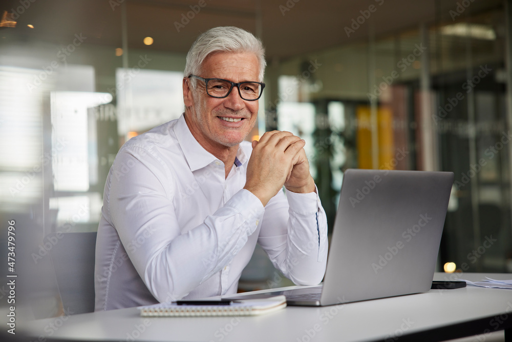 Mature entrepreneur smiling while sitting at desk