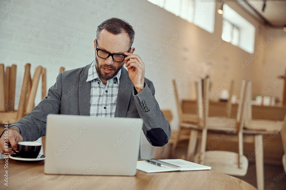 Bearded man working on notebook in cafe Bearded man working on notebook in cafe