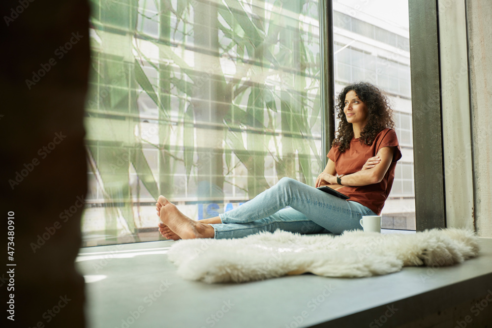 Businesswoman with arms crossed sitting by window Businesswoman with arms crossed sitting by window