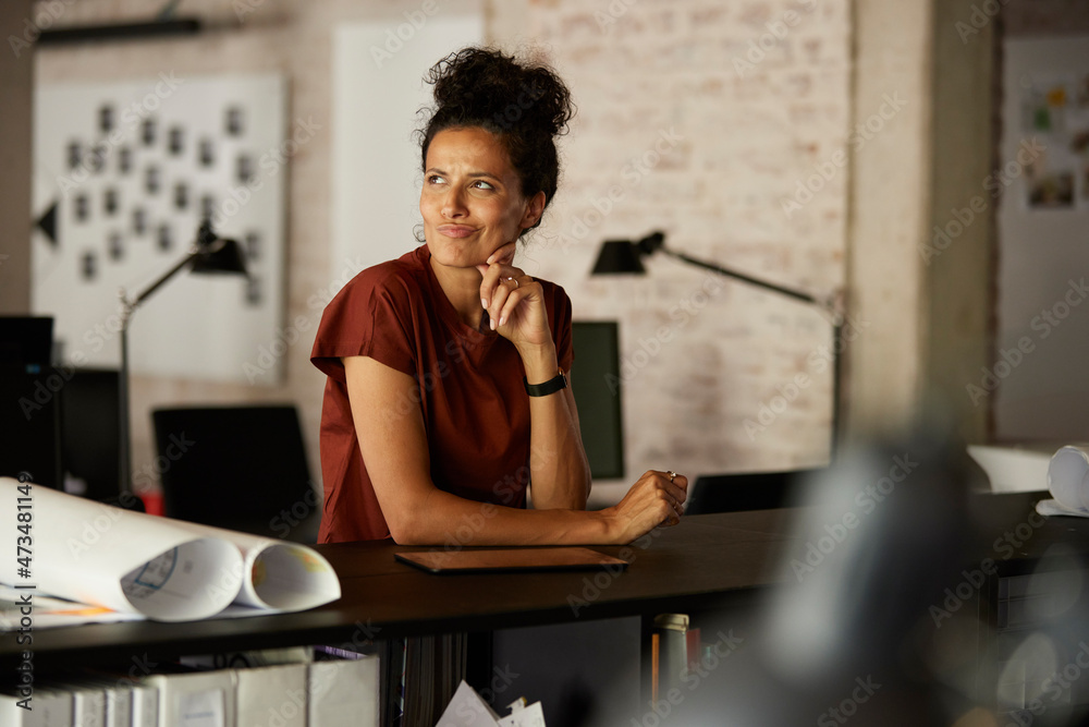 Businesswoman with hand on chin contemplating while puckering at workplace Businesswoman with hand on chin contemplating while puckering at workplace