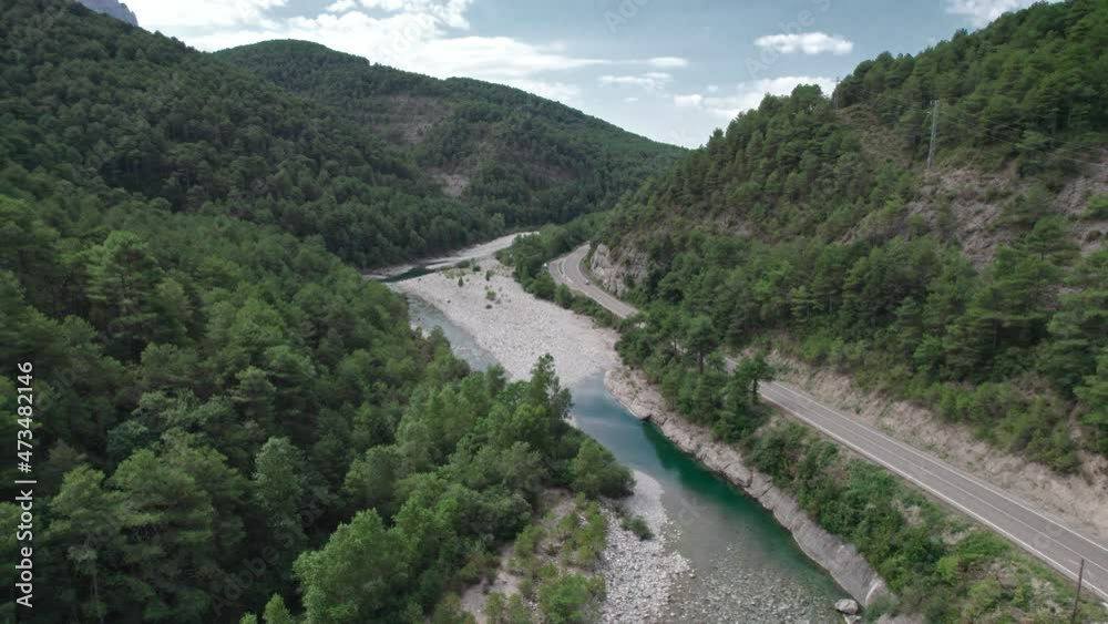 Mountain river with a rocky bank, top view. Green trees and a narrow path meander alongside. Mountain river with a rocky bank, top view. Green trees and a narrow path meander alongside.