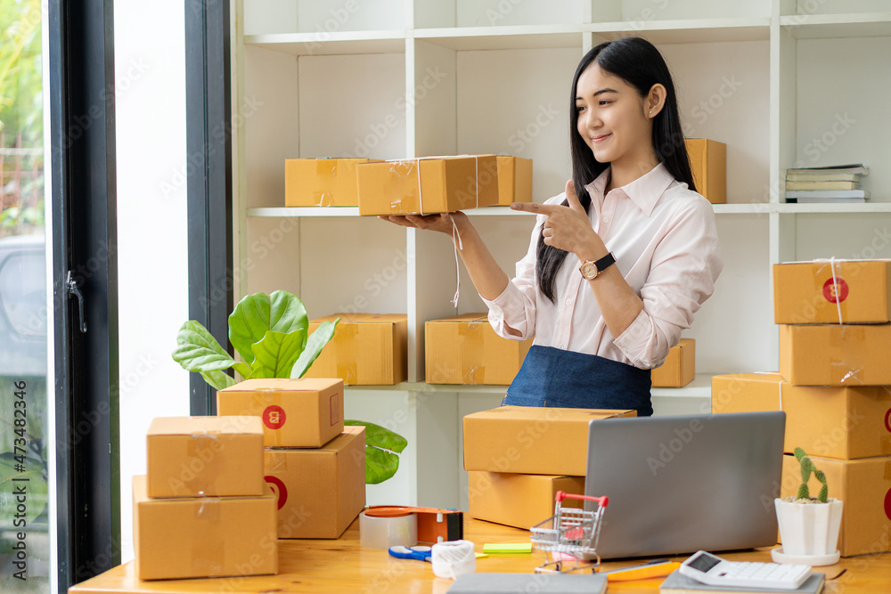 Starting a small business entrepreneur, SME, or freelance Asian woman working with boxes and laptops at home, online sales ideas, e-commerce, shipping, packaging, online marketing, and shipping. Starting a small business entrepreneur, SME, or freelance Asian woman working with boxes and laptops at home, online sales ideas, e-commerce, shipping, packaging, online marketing, and shipping.