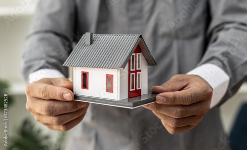 Model of a house placed on a person's hand, a housing salesman in the project, a portrait holding a house project to the front similar to delivering homes to customers. Real estate trading ideas.