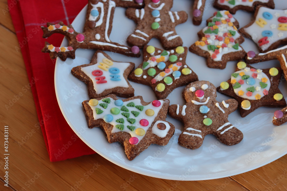 Homemade Christmas glazed and decorated cookies in various shapes on plate on wooden table 
