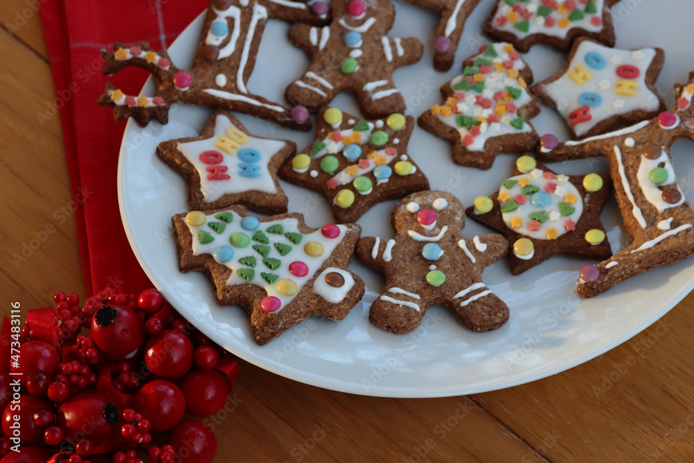 Homemade Christmas glazed and decorated cookies in various shapes on plate on wooden table 