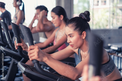 group friends working out on exercise bike and wearing sportswear in fitness or gym center, strength sporty and weight loss concept