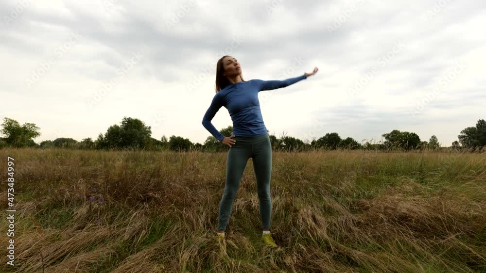 Young brunette woman doing stretching outdoors in a dry field. Workout. Outdoor exercise