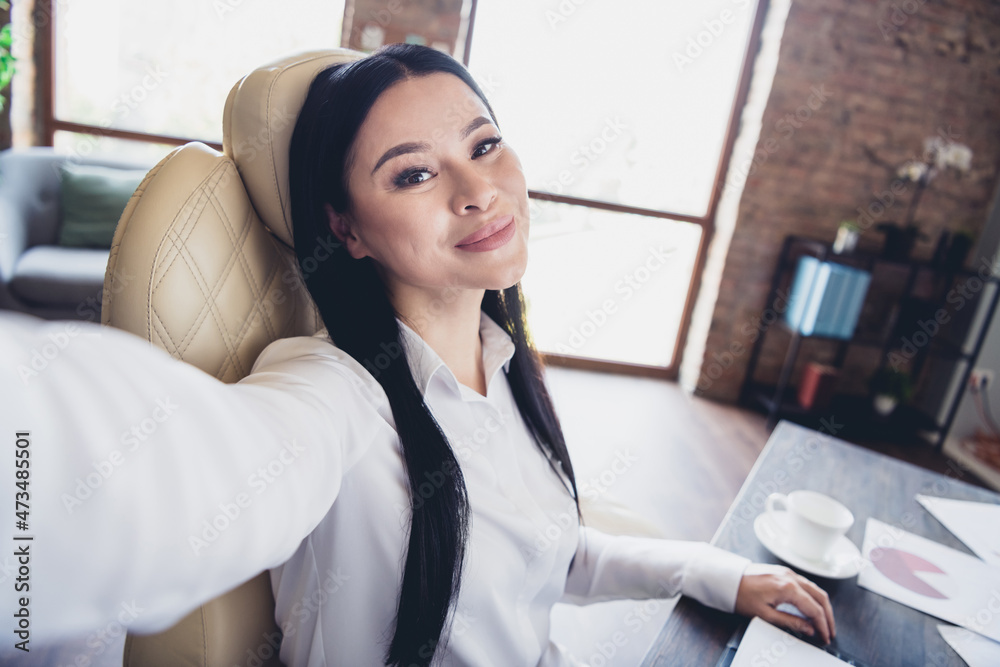 Photo of pretty positive person sit chair make selfie recording video daylight loft room indoors Photo of pretty positive person sit chair make selfie recording video daylight loft room indoors