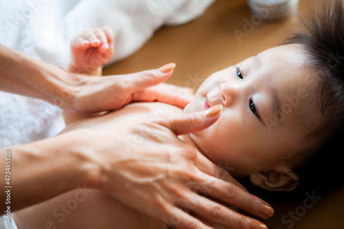 赤ちゃんの肌に保湿クリームを塗る母親 photo