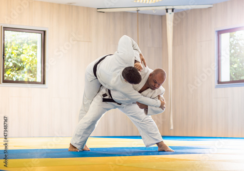 Two adult man practicing judo in the sports hall.