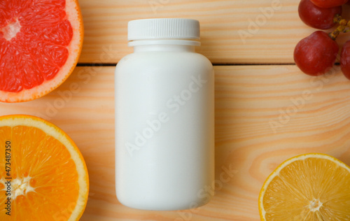 Vitamins mockup. Blank Medicine bottle for vitamins on a background of citrus fruit slices. lemon. Orange. Grapefruit. Wooden background
